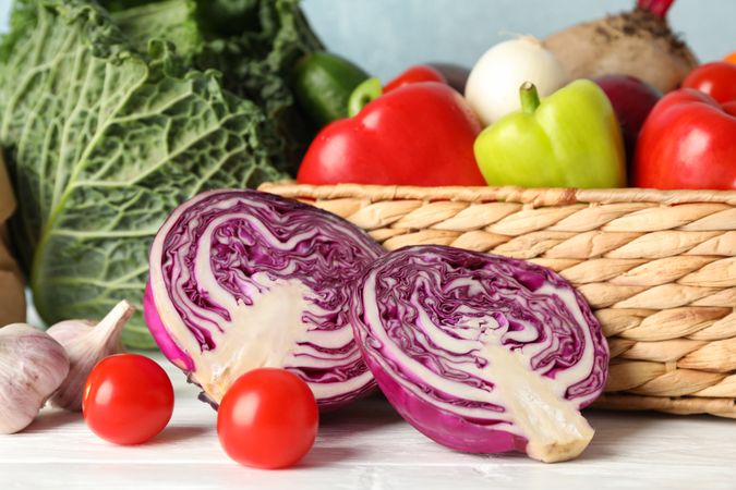 Wicker basket and vegetables on wooden background, close up
