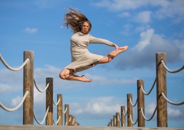 Woman with textile posing in air on footbridge
