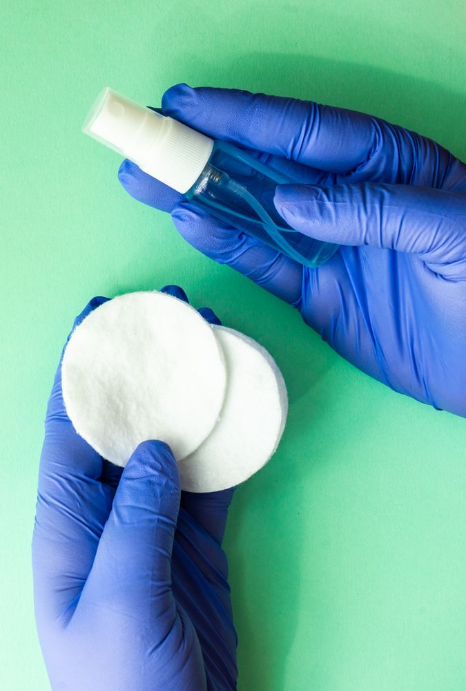 Covid-19 virus concept of hands in latex gloves holding anti bacterial wash and cotton swabs