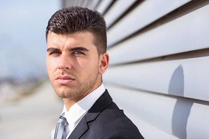 Man in suit next to wall looking directly at camera
