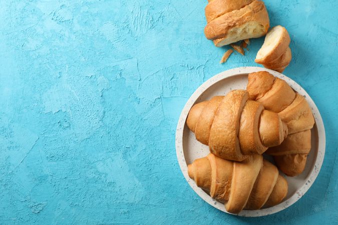 Tray with croissants on blue background, space for text