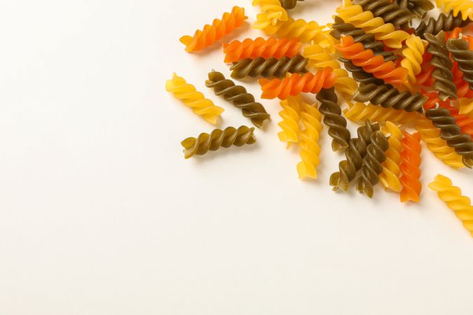Color pasta on blank background, space for text. Dry uncooked whole pasta
