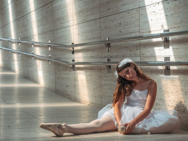 Ballerina sitting on floor stretching graceful leg