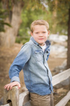 Handsome Young Boy Against Fence in Park