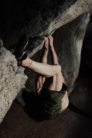 Man practicing rock climbing among large rocks in a forest