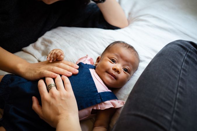 New born baby with parents hands on her stomach