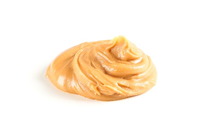 Creamy peanut butter isolated on light background. A traditional product of American cuisine