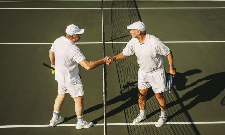Fit older men shaking hands before tennis match