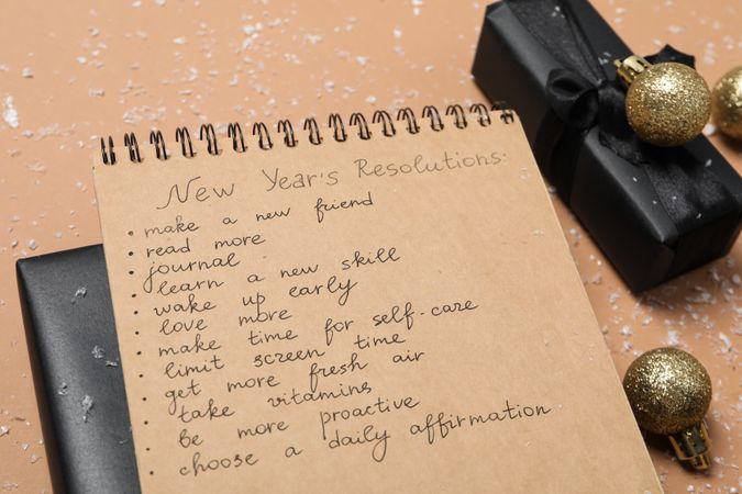 Gift boxes and notepad with list on beige background, close up