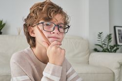 Puzzled boy in glasses looking at screen