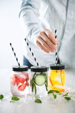 Man with mason jars of infused water and striped straws