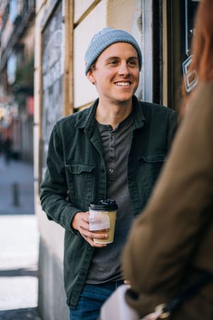 Man standing outside cafe with to go cup