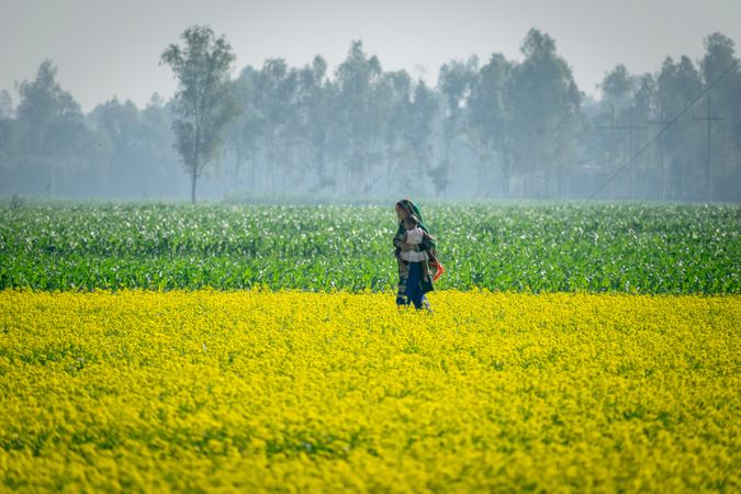 Mother holding her baby in mustard flower field in Bangladesh
