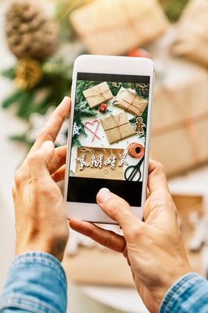 Anonymous person photographing Christmas presents on phone