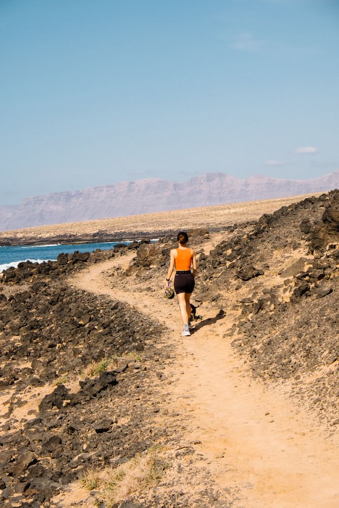 Back of woman walking on trail next to ocean
