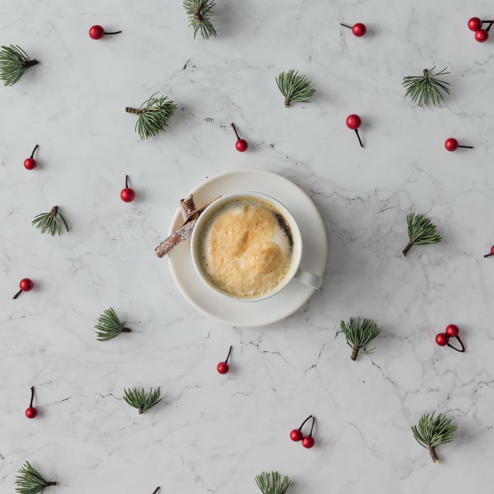Holly and pine pattern on marble background with coffee