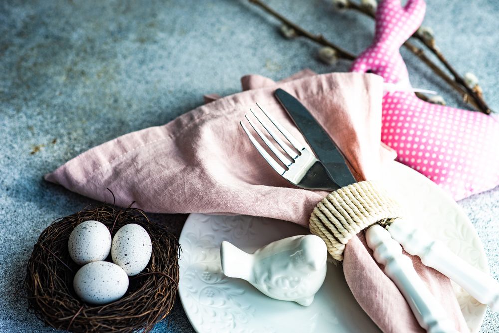Easter table setting with eggs, bird figurine and pink napkin