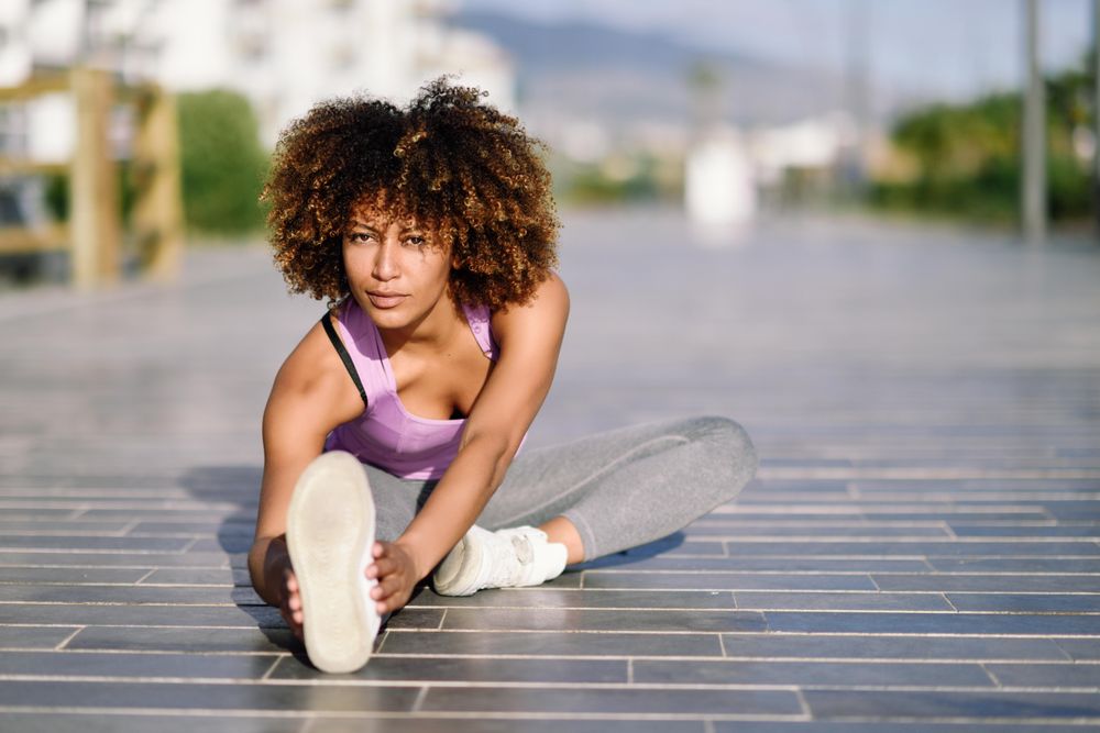 Female with afro stretching legs with city scape in the background