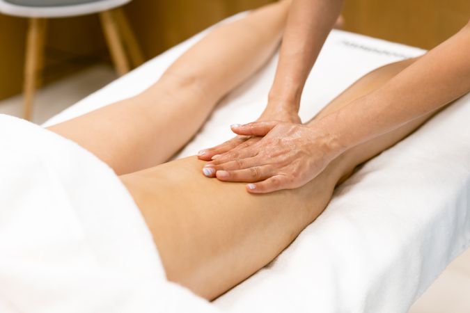 Masseuse giving a hamstring massage to a woman with both her hands