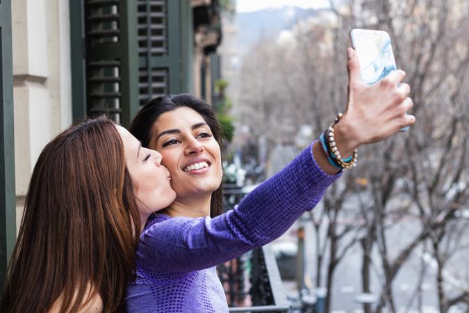 Happy lesbian couple taking selfie on balcony
