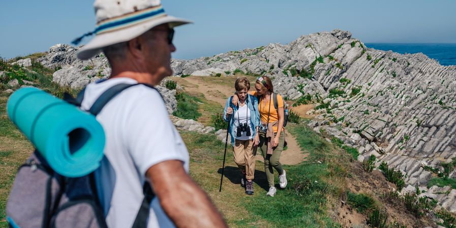 Mature man in foreground of his family trekking up the hill