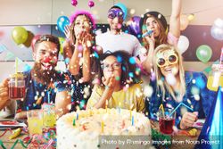 Friends celebrating at a birthday party with confetti, drinks and cake 43mrP0