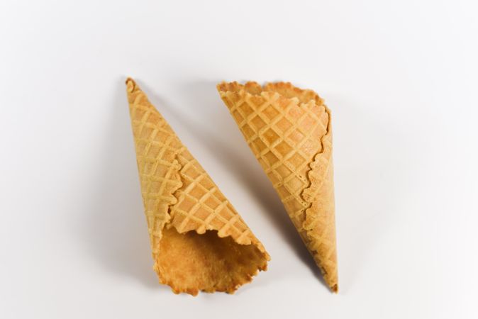 Two waffle cones lying on plain table
