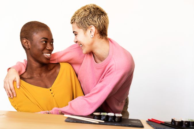 Loving lesbian couple laughing together over sushi lunch