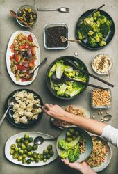Vegan dinner table setting with healthy dishes in plates on table and woman’s hands taking food