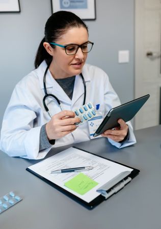 Female doctor doing online consultation showing pills for treatment