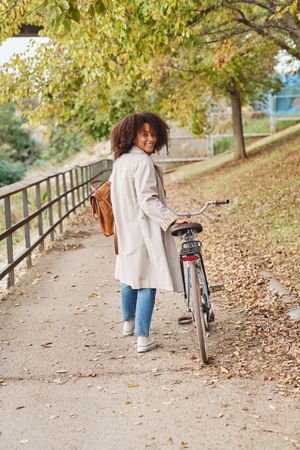 Smiling female with bicycle in autumn park
