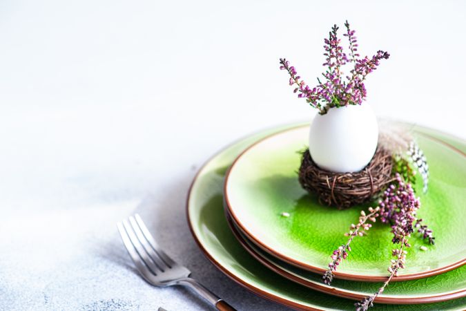 Easter spring card concept with egg in small nest on green plate
