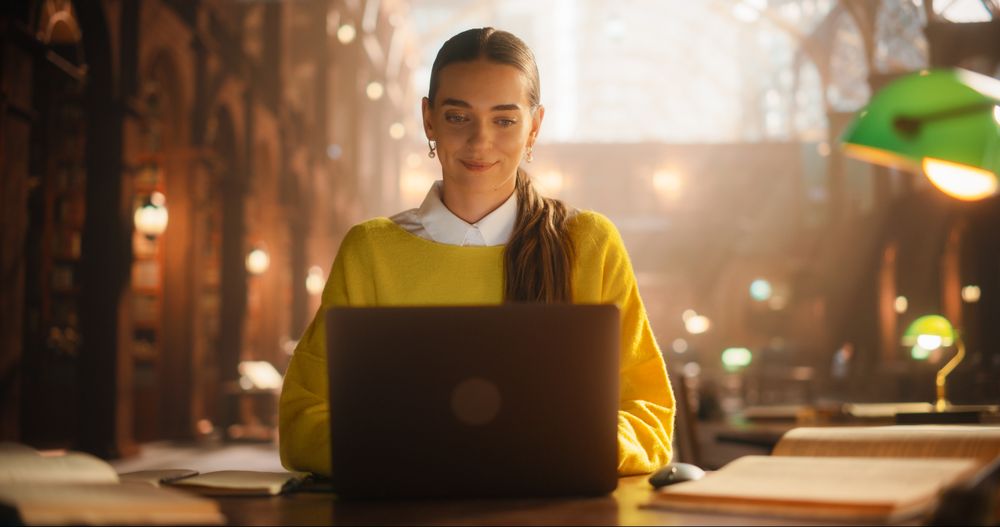 Engaged Female Student Using Laptop for Online Learning in a Cozy Library.