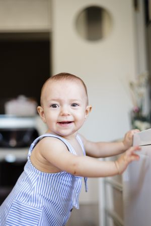 Happy baby sitting on floor in kitchen