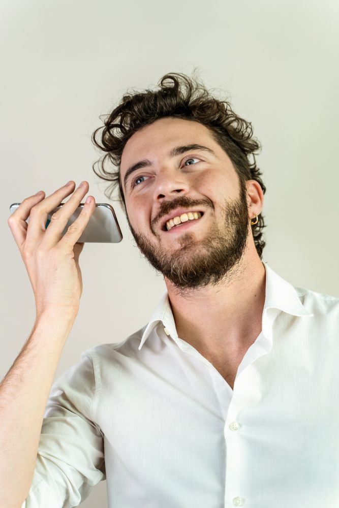 Happy young man listening to a voice message on his smartphone.