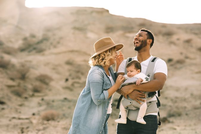 Diverse parents dancing while standing with baby