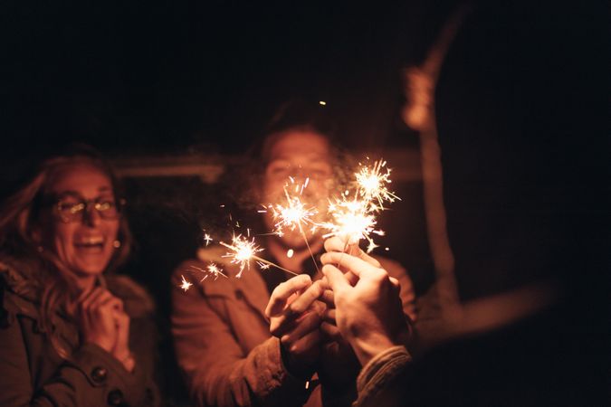 Man holding burning fire sparkler sticks in hands enjoying with friends