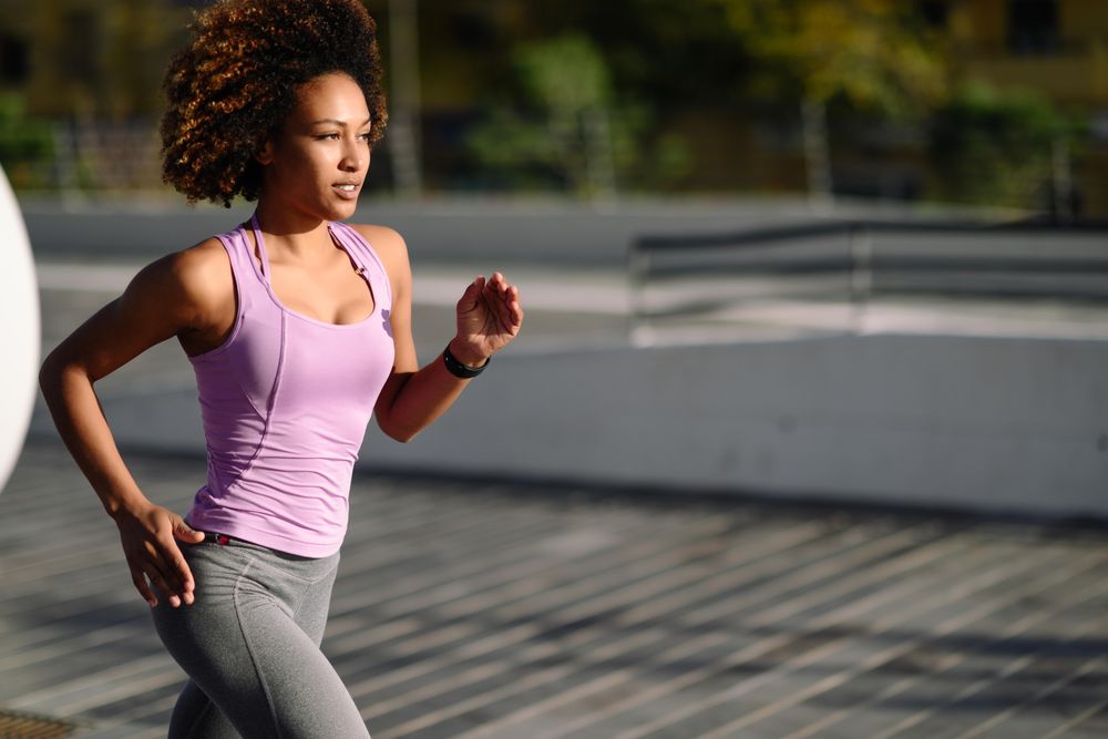 Woman with afro hairstyle running outside in sports wear
