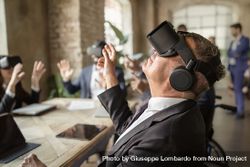 Group of office workers wearing VR goggles focus on older man in suit 5zrRwj