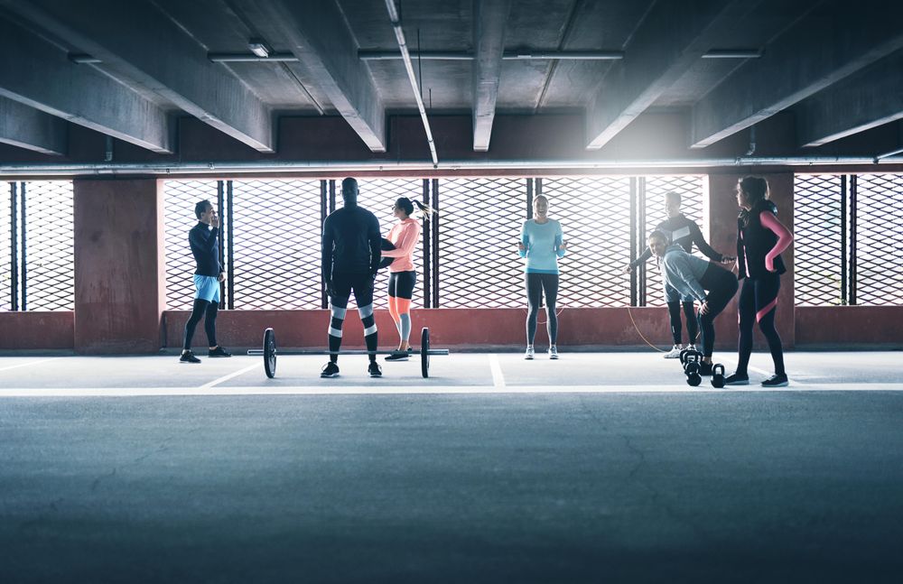 Group of diverse people doing circuit training near bright window