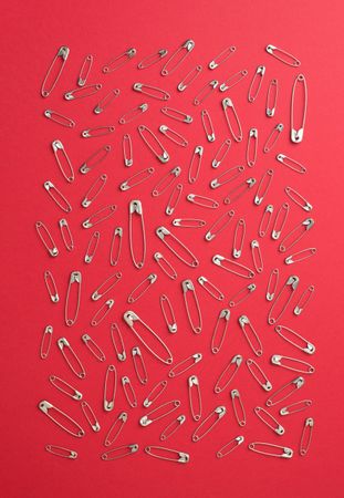 Scattered safety pins on red background