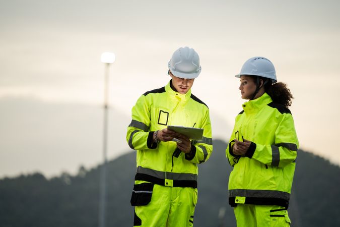 Engineer worker watching work monitor on digital tablet at refinery factory at night