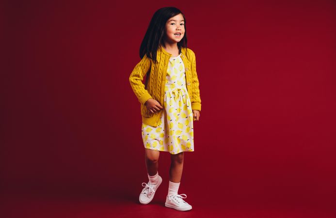 Cute Chinese girl wearing yellow dress against red background