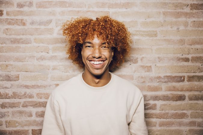 Portrait of a young man with a brick wall background.