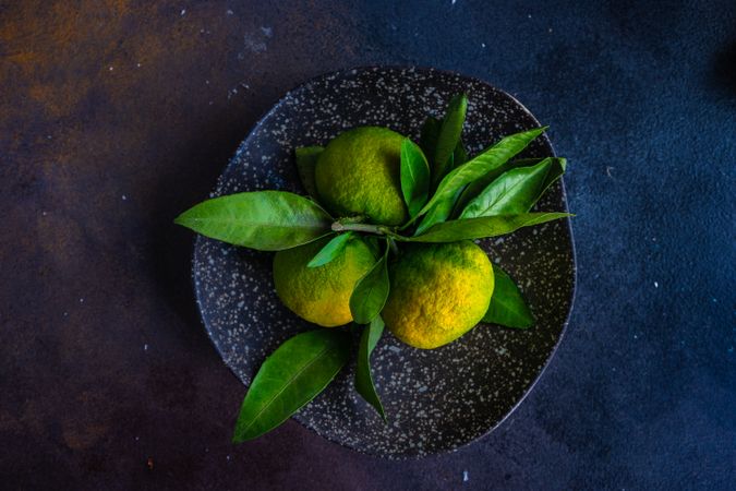 Top view of fresh green tangerines in grey ceramic bowl with space for text