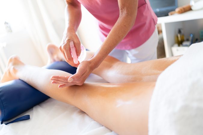 Masseuse working on calves of woman in spa
