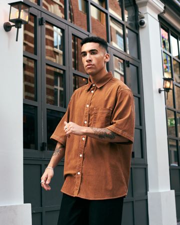 Stylish young man with tattoos in corduroy shirt