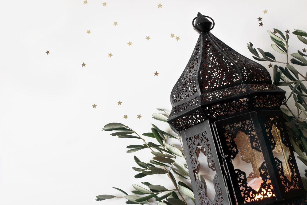 Glowing dark Moroccan, Arabic lantern and olive tree twigs isolated on table background.