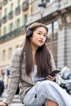 Young Asian woman listening to music with smartphone in the city