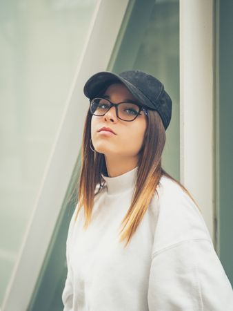 Young woman with glasses standing against wall